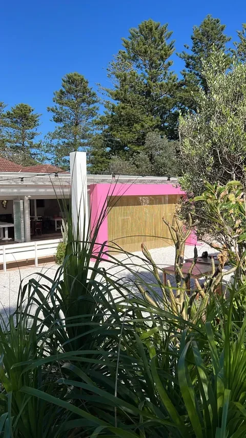 Pink architectural joinery viewed through garden planting